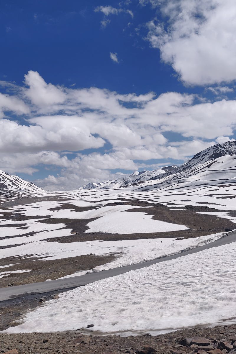 Serene winter view of Baralacha La Pass with snow-capped mountains under a blue sky.